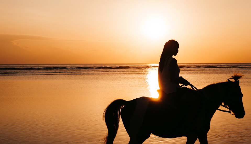 Female riding horse on beach